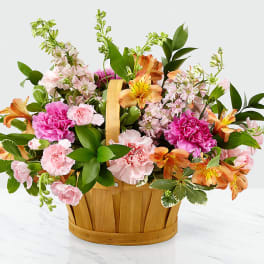 Mixed pink and orange flowers in a wooden basket