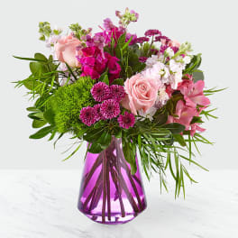 Pink and magenta mixed bouquet in a purple glass vase