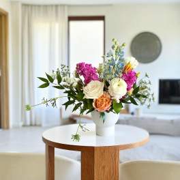Mixed bouquet in a white vase with pink, white, blue, and orange flowers