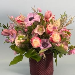 Mixed pink and purple flower arrangement in a textured burgundy vase
