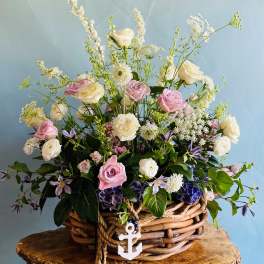 Basket arrangement of pink and white roses with delicate filler flowers