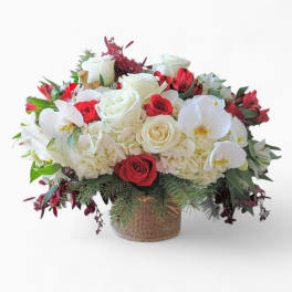 Low red and white arrangement with roses, orchids, and hydrangeas in a burlap-wrapped vase