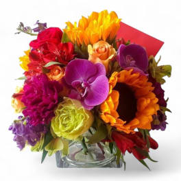 Colorful bouquet of roses, orchids, and sunflowers in a clear glass vase
