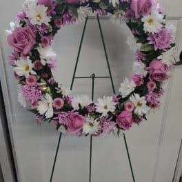 Pink and white floral wreath on a green easel stand