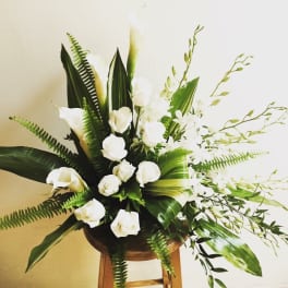 White calla lilies and roses in a wooden stand arrangement