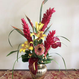 Tropical floral arrangement in a gold vase with red and yellow blooms