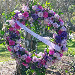 Heart-shaped floral wreath with a memorial ribbon on an easel