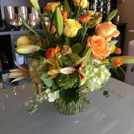 Mixed bouquet of orange and yellow flowers in a patterned vase