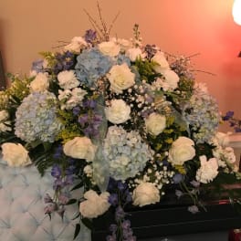 Large floral arrangement with white roses, blue hydrangeas, and purple flowers