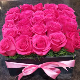 Pink roses arranged in a black box with a pink ribbon