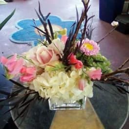Mixed bouquet in a clear square vase with pink and cream flowers
