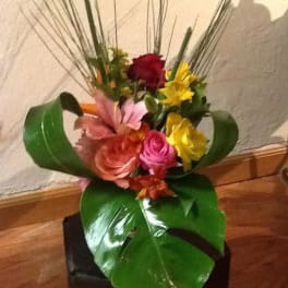 Mixed bouquet with roses and lilies in a black container