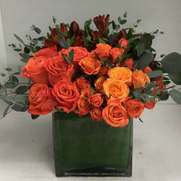Orange and yellow roses arranged in a green vase