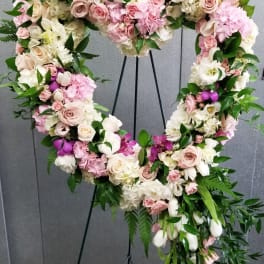 Heart-shaped floral wreath with pink and white roses on a stand