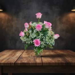 Pink roses arranged in a clear glass vase with baby's breath