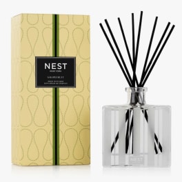Reed diffuser in a clear glass bottle with black reeds and a yellow box