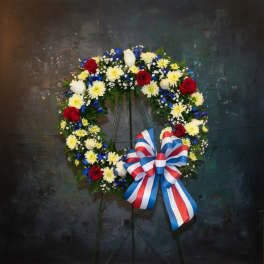 Circular floral wreath with red, white, and blue flowers and a striped bow