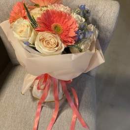 Bouquet of pink gerbera daisies and cream roses wrapped in pale paper