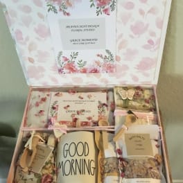 Floral gift box with bath items and a mug labeled Good Morning