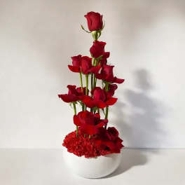 Tall arrangement of red roses in a white vase