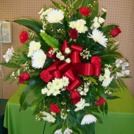 Standing floral spray with red and white flowers and a large red ribbon