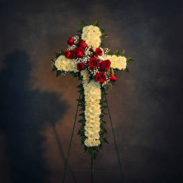Standing cross-shaped floral tribute with red roses and white flowers