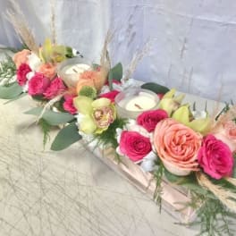 Low floral centerpiece with pink and peach roses and candles