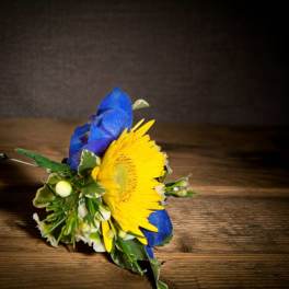 Blue and yellow floral boutonniere on a wooden surface
