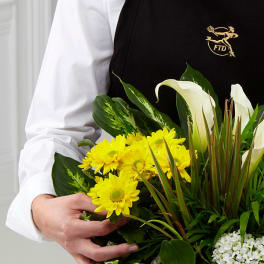 Person holding a bouquet with yellow daisies and white calla lilies