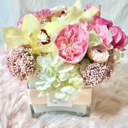 Pink and cream floral arrangement in a square glass vase