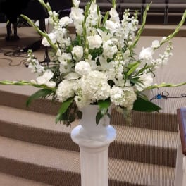 White floral arrangement in a tall pedestal vase