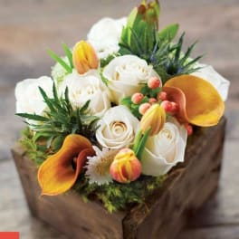 White roses and orange calla lilies in a wooden box