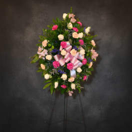 Standing floral wreath with pink and white flowers on a dark easel