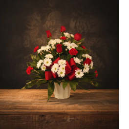 Red roses and white daisies arranged in a white vase
