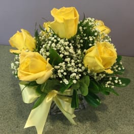 Yellow roses arranged with baby's breath in a glass vase with a ribbon