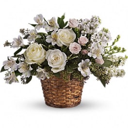 White roses and small white flowers arranged in a woven basket