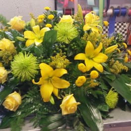 Yellow roses and lilies arranged in a low, wide floral display
