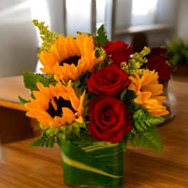 Sunflowers and red roses arranged in a green glass vase