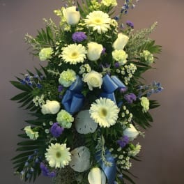 Standing floral spray with white roses and gerbera daisies, blue ribbon accents