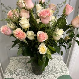 Pink and white roses arranged in a clear glass vase