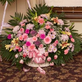Large pink and white funeral spray with ribbon in a basket