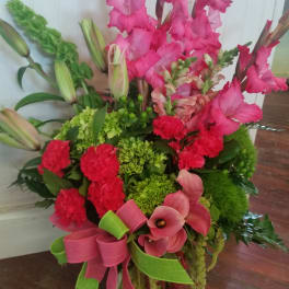 Pink gladiolus and calla lilies with red carnations in a ribboned bouquet