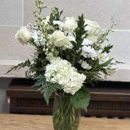 White roses and hydrangeas in a clear glass vase