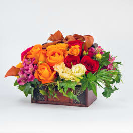 Orange and red roses in a decorative wooden box with ivy