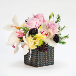Pink roses and white orchids in a textured square vase
