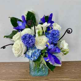 Blue and white floral arrangement in a square glass vase