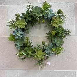 Succulent wreath with green and blue rosettes on a wall
