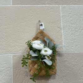 White flowers and greenery in a woven wall basket