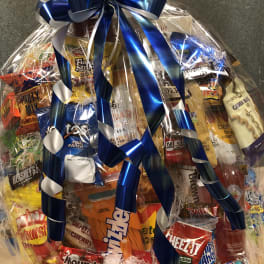 Gift basket of assorted snacks wrapped in cellophane with a blue ribbon