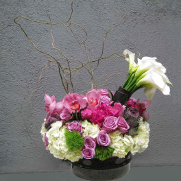 Pink and white floral arrangement in a black pedestal vase